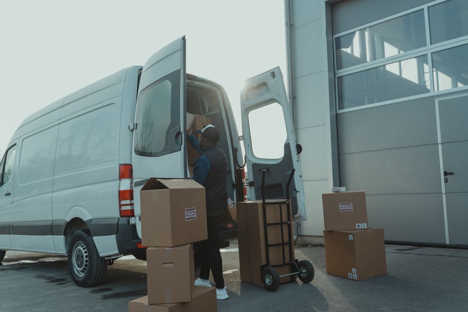 Utovar kutija u bijeli kombi ispred skladišta